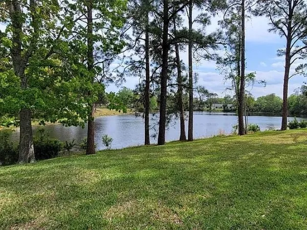 a view of a white house with a big yard and large trees