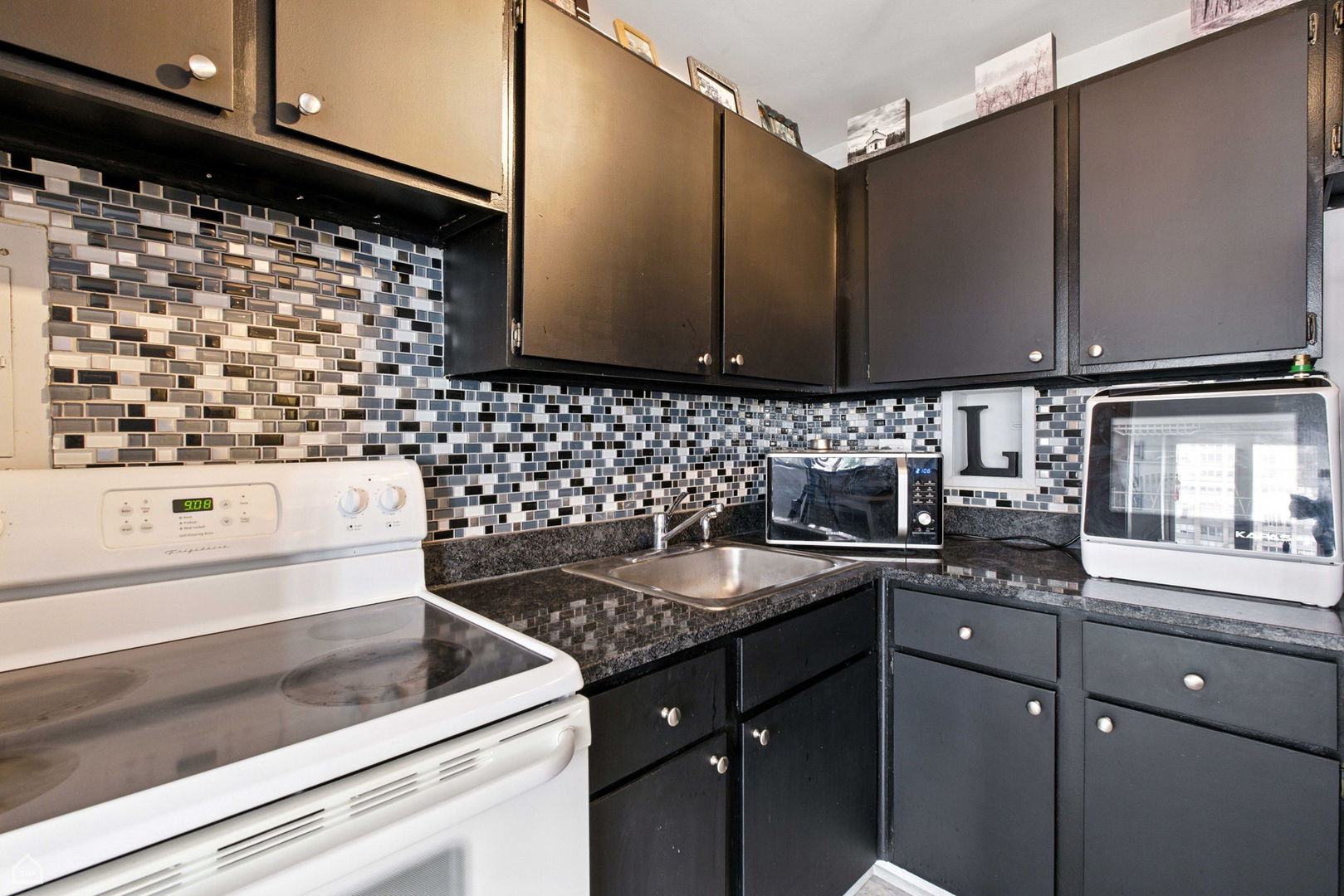 700 West Bittersweet Place, Unit 904 Chicago, IL 60613 - Photo 3 of 11 a kitchen with granite countertop a sink and a stove