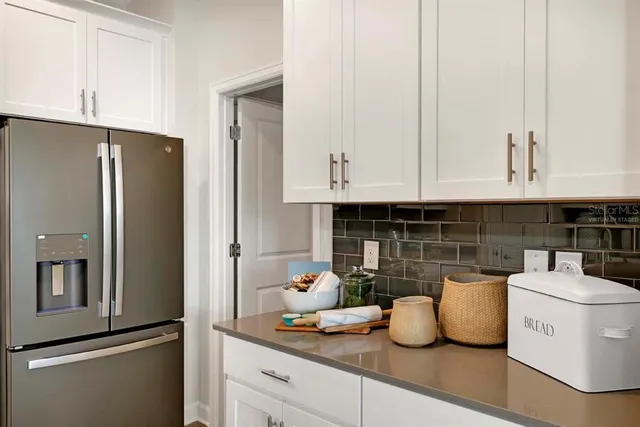 a kitchen with stainless steel appliances granite countertop a refrigerator and white cabinets