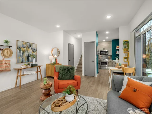 a living room with furniture kitchen view and a wooden floor