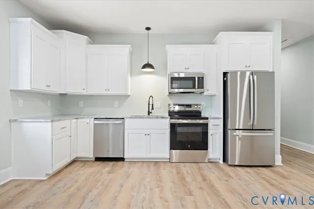 a kitchen with granite countertop a refrigerator and a stove top oven