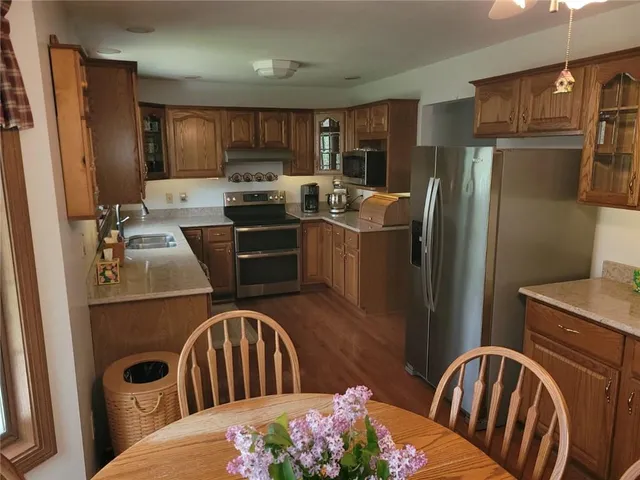 a kitchen with stainless steel appliances granite countertop a refrigerator a stove top oven a sink dishwasher and wooden cabinets