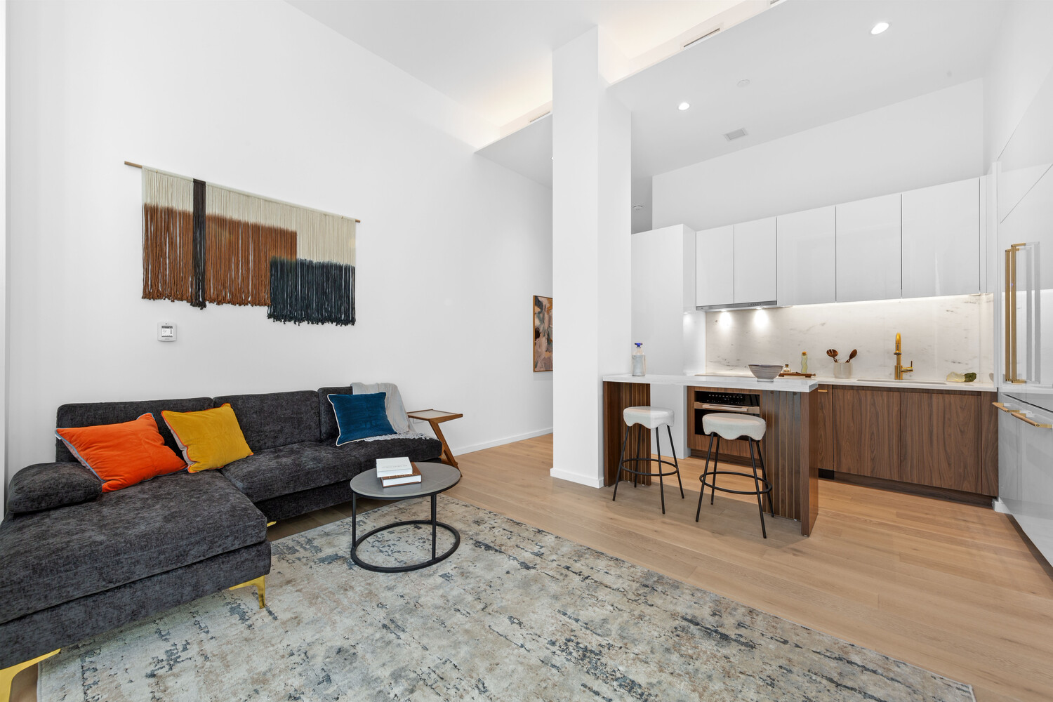 a living room with furniture and a flat screen tv with kitchen view