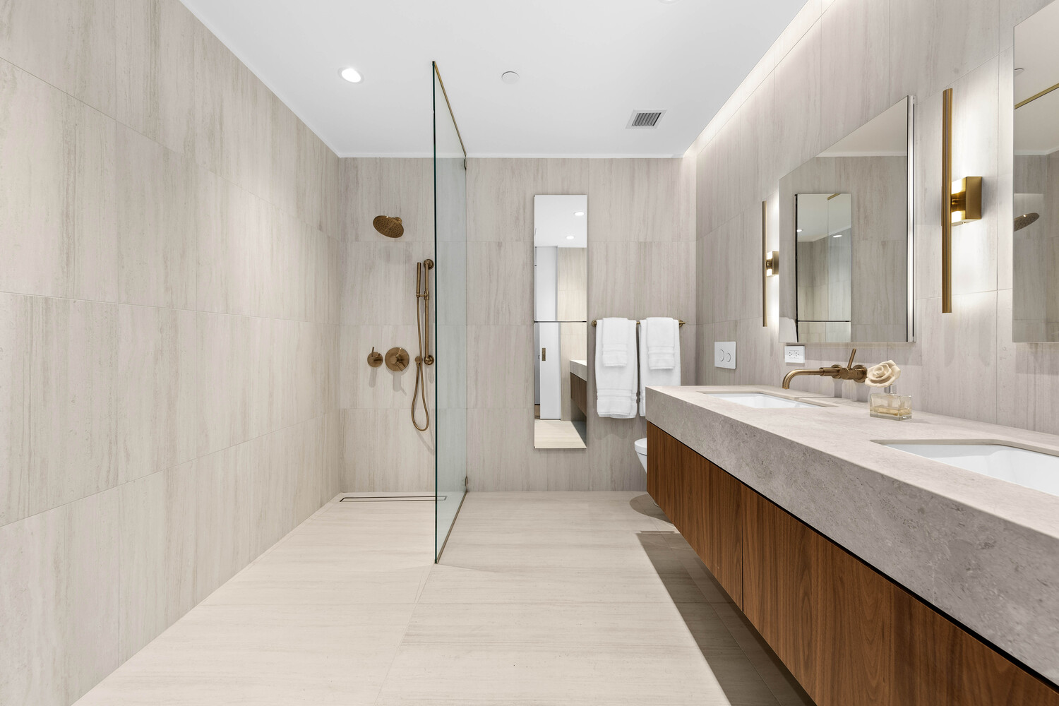330 Grand Street, Unit 1B Manhattan, NY 10002 - Photo 5 of 14 a bathroom with a double vanity sink a large mirror and shower