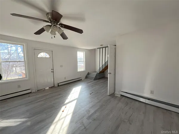 an empty room with wooden floor fan and windows