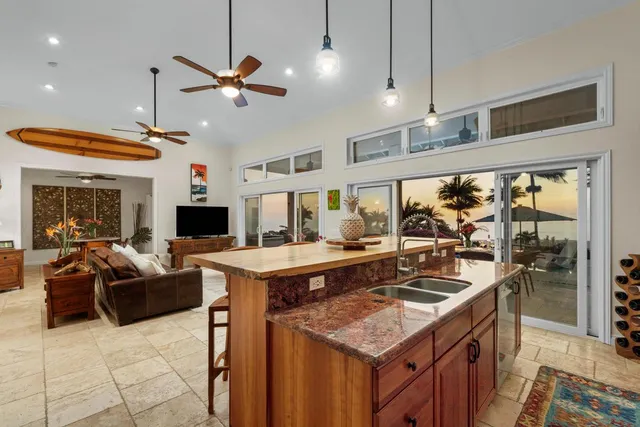 a kitchen with a stove a counter space a sink and living room view