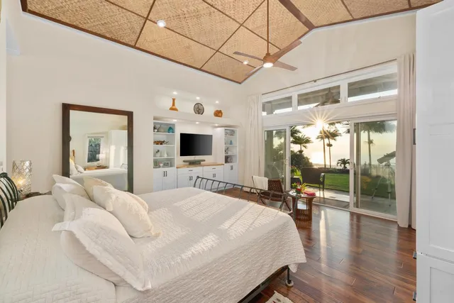 a spacious bedroom with a bed and a flat tv screen on dresser