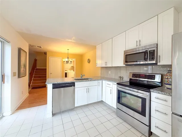 a kitchen with granite countertop white cabinets stainless steel appliances and a counter space