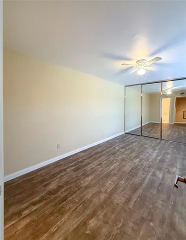 an empty room with chandelier fan and windows