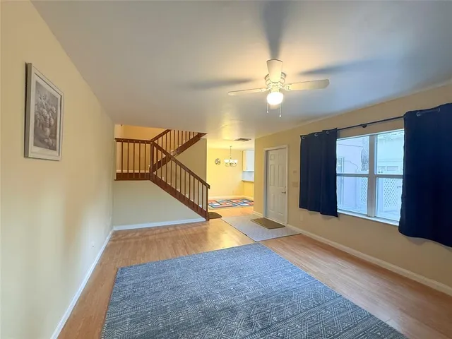 wooden floor in an empty room with a window and a kitchen