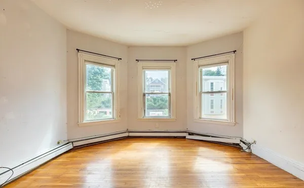an empty room with wooden floor and windows