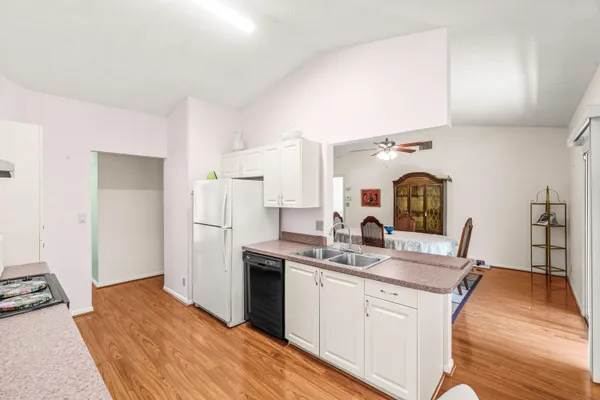 a kitchen with stainless steel appliances a stove a sink dishwasher and a refrigerator with wooden floor