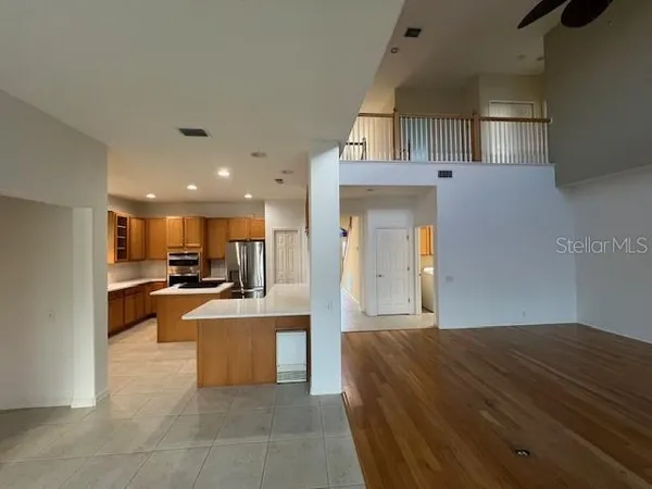 a living room with stainless steel appliances furniture a rug and a kitchen view