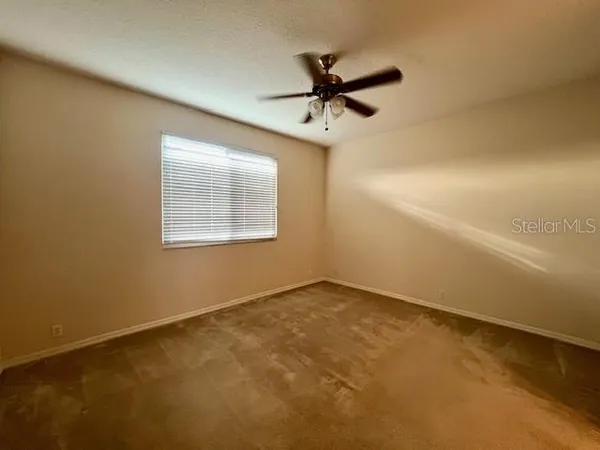 an empty room with a window and a fan