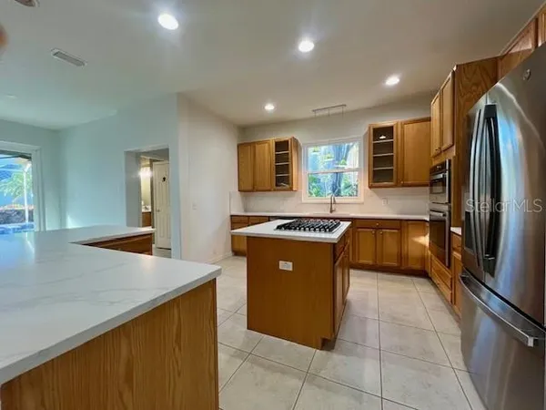 a large kitchen with stainless steel appliances granite countertop a sink and a refrigerator
