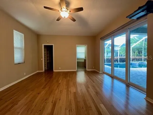a view of empty room with wooden floor and fan