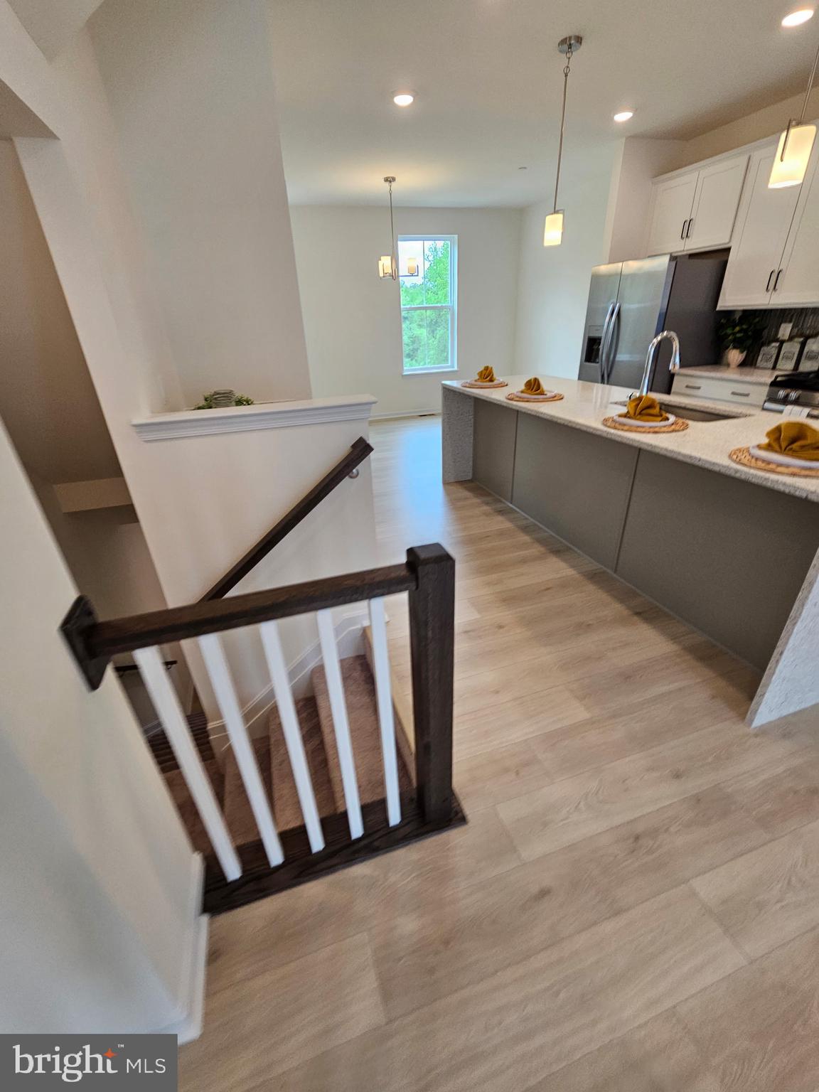 7304 Roxy Run, Unit 8 Clinton, MD 20735 - Photo 6 of 27 a large white kitchen with kitchen island a sink a stove a wooden floor and a shower