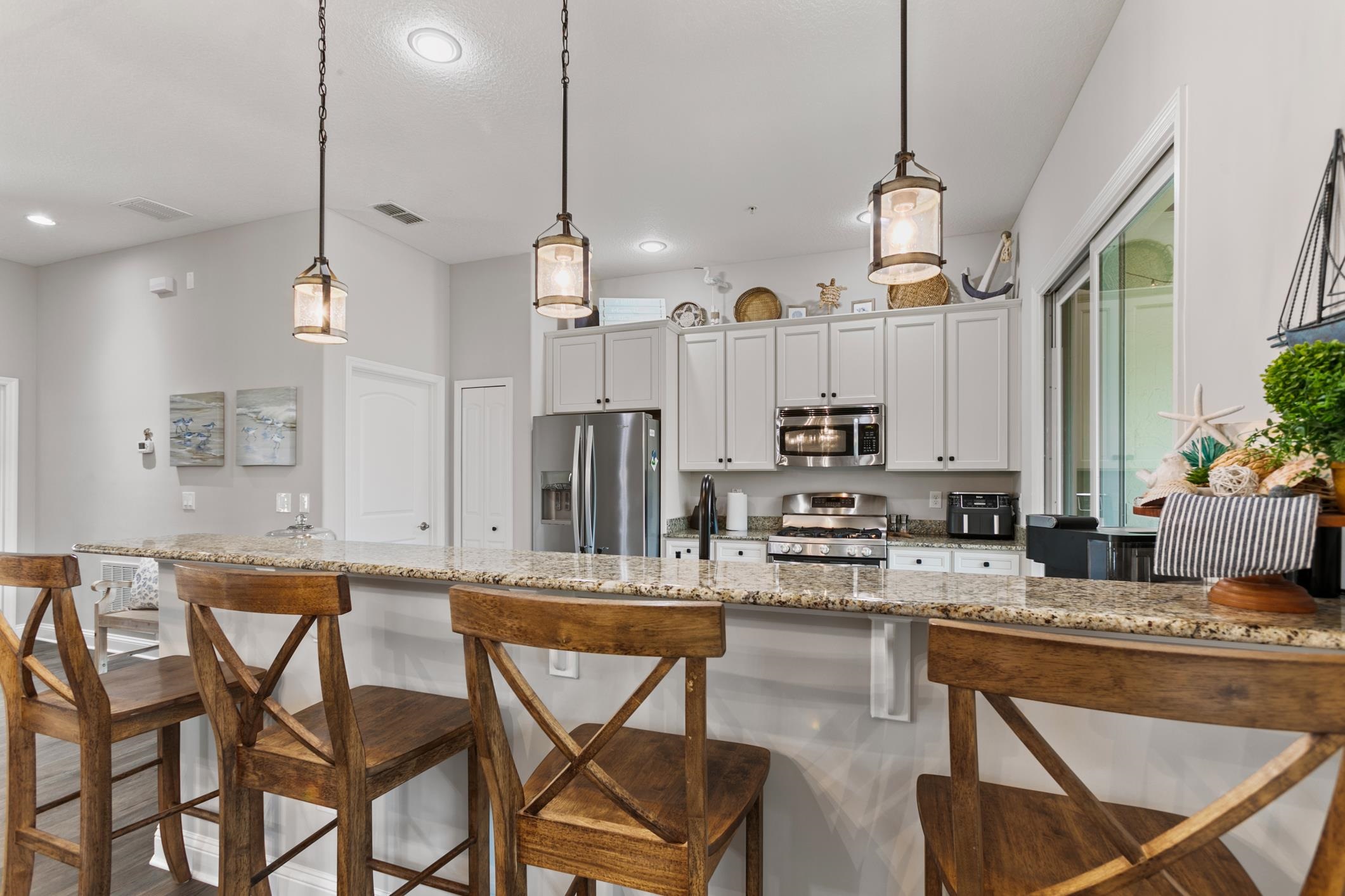 a kitchen with stainless steel appliances kitchen island granite countertop a table chairs and a refrigerator