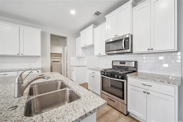 a kitchen with granite countertop a sink and steel appliances