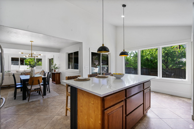 432 Calnette Drive Sandy, UT 84070 - Photo 7 of 48 Kitchen island with a light-toned countertop, wood-finish cabinetry, and two pendant light fixtures