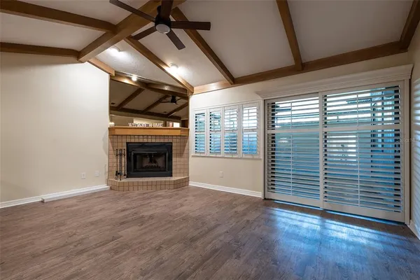 an empty room with wooden floor a fireplace and windows