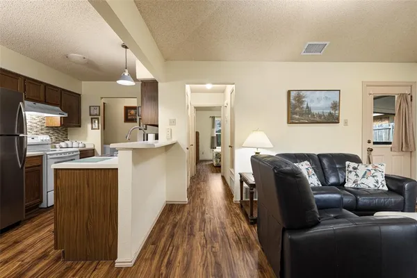 a living room with stainless steel appliances furniture and a kitchen view