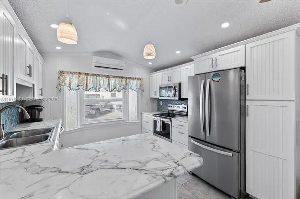 a kitchen with granite countertop a refrigerator oven a sink a stove and a refrigerator