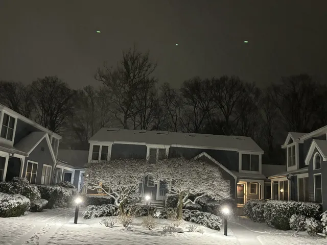 a front view of a house with a big yard and large trees