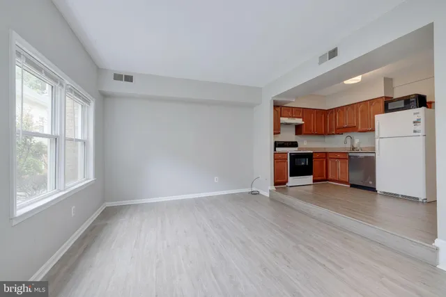 a view of kitchen with stainless steel appliances wooden floor and a large window