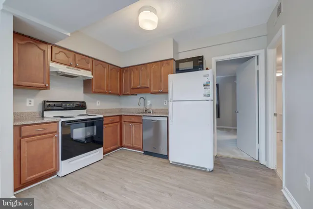 a kitchen with a refrigerator a stove top oven a sink and cabinets