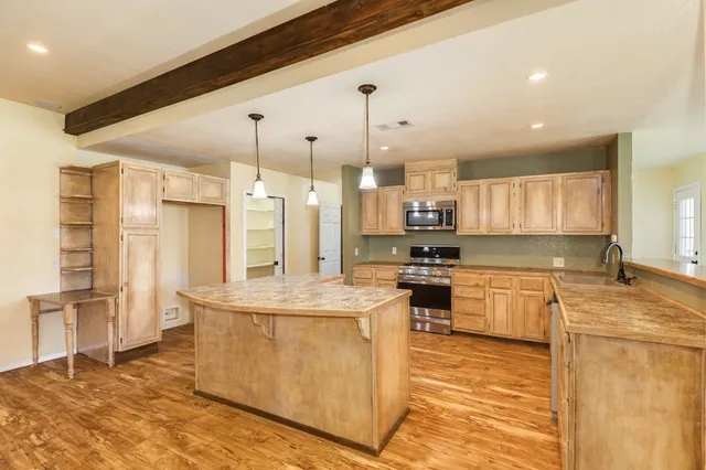 a large kitchen with stainless steel appliances kitchen island granite countertop a stove a sink a refrigerator and a granite counter tops with white cabinets