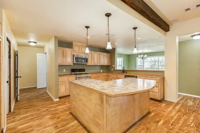 a kitchen with stainless steel appliances granite countertop a sink a counter space and a window