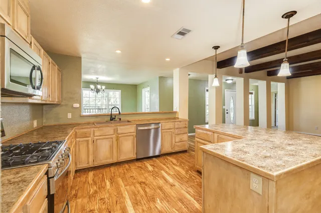 a large kitchen with stainless steel appliances granite countertop a sink and cabinets