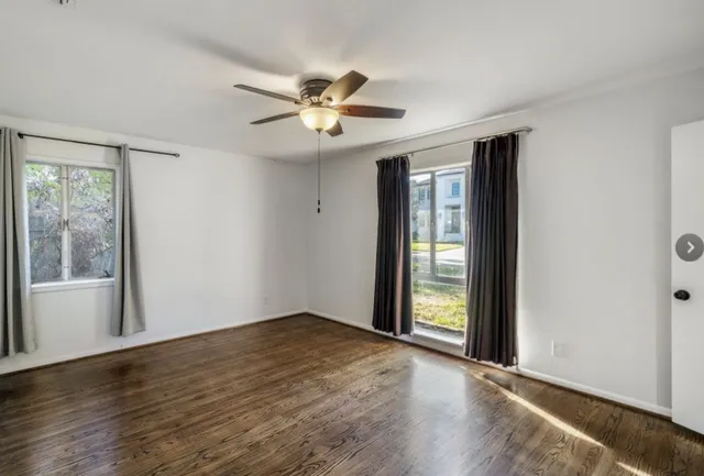 a view of an empty room with a window and wooden floor