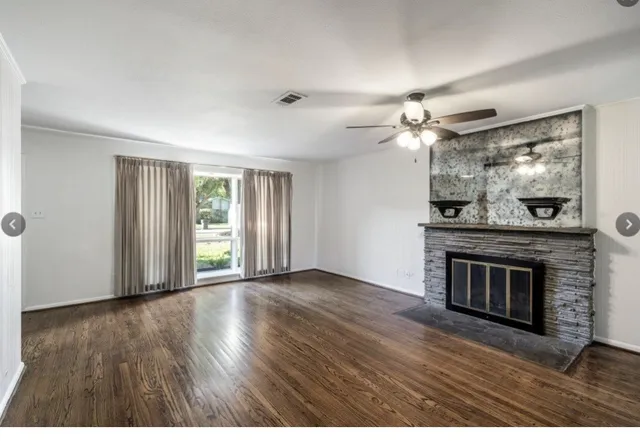 an empty room with wooden floor fireplace and windows