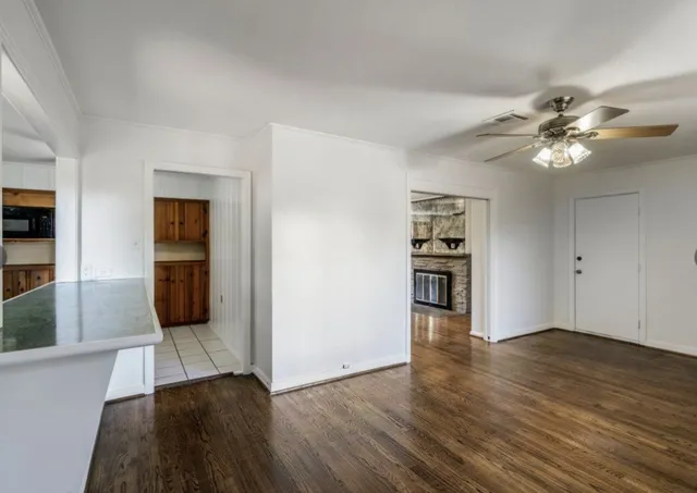 a view of a kitchen with an empty space a ceiling fan and wooden floor