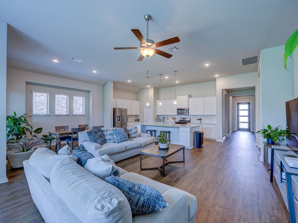 229 Heartleaf Road San Marcos, TX 78666 - Photo 21 of 40 An inviting open-concept living area boasts a modern kitchen and natural wood-toned flooring throughout.