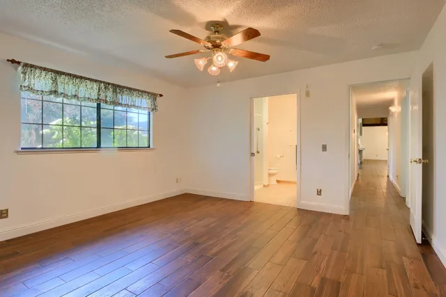 a view of an empty room with window and wooden floor