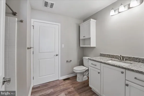 a bathroom with a granite countertop toilet a sink and a mirror