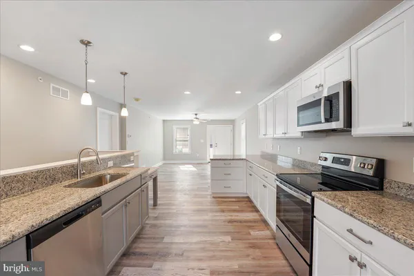 a large kitchen with granite countertop a sink and dishwasher stove top oven with wooden floor