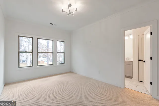 an empty room with chandelier fan and windows