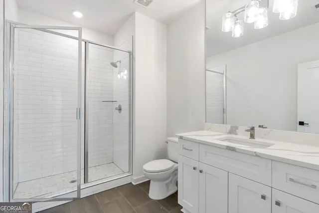 a bathroom with a toilet a sink a glass door a shower a mirror and vanity