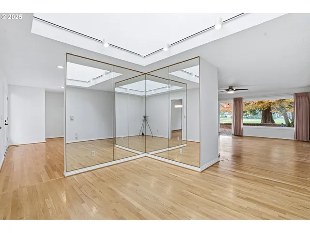 a view of an empty room with window and wooden floor
