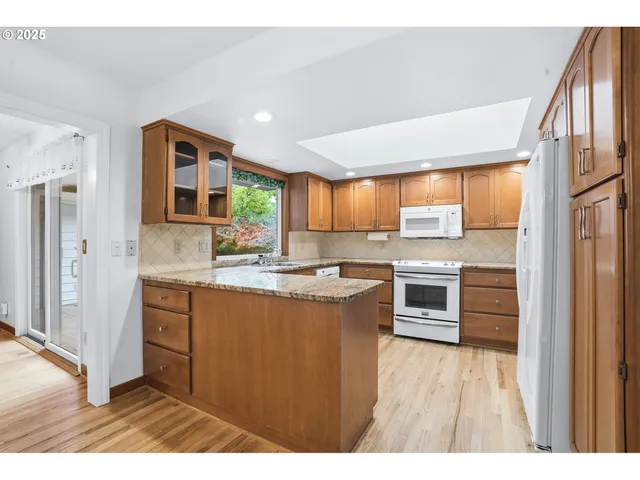 a kitchen with stainless steel appliances granite countertop a refrigerator a sink dishwasher a stove with wooden cabinets