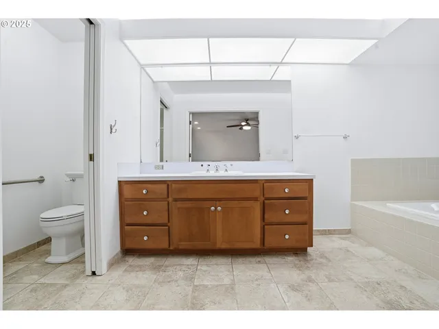 a bathroom with a granite countertop toilet a sink and a mirror