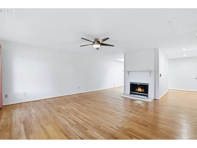 a view of an empty room with a ceiling fan and wooden floor