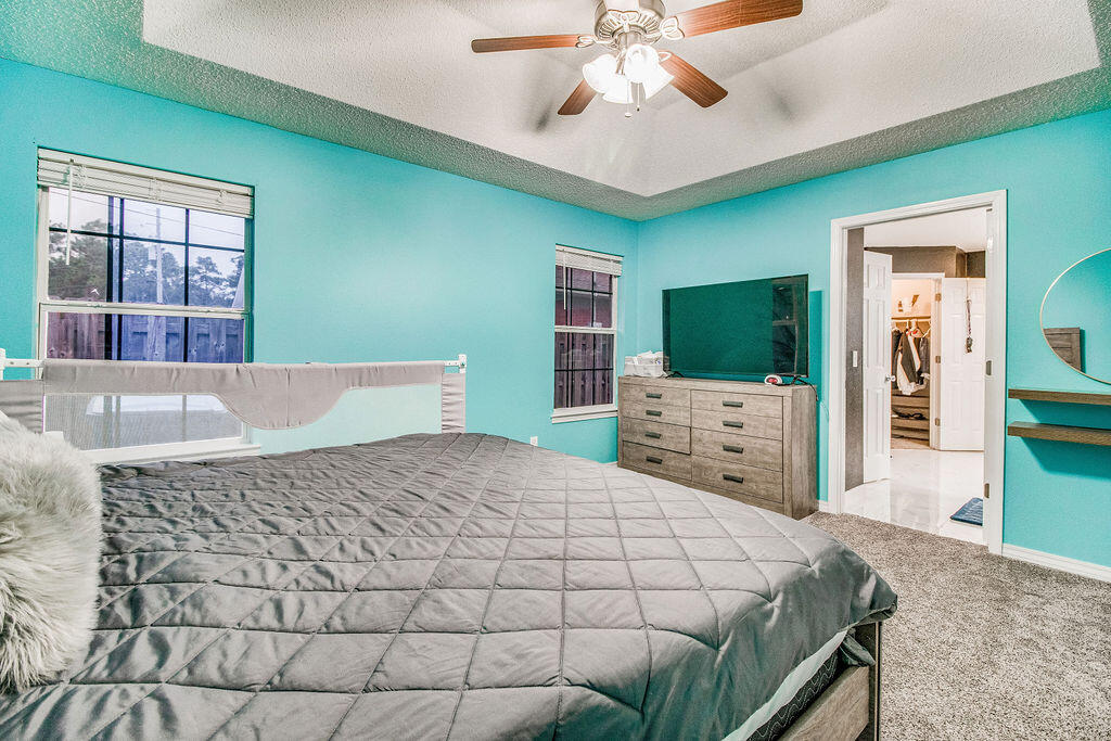 2442 Raider Lane Navarre, FL 32566 - Photo 21 of 46 a bedroom with a large bed and a chandelier