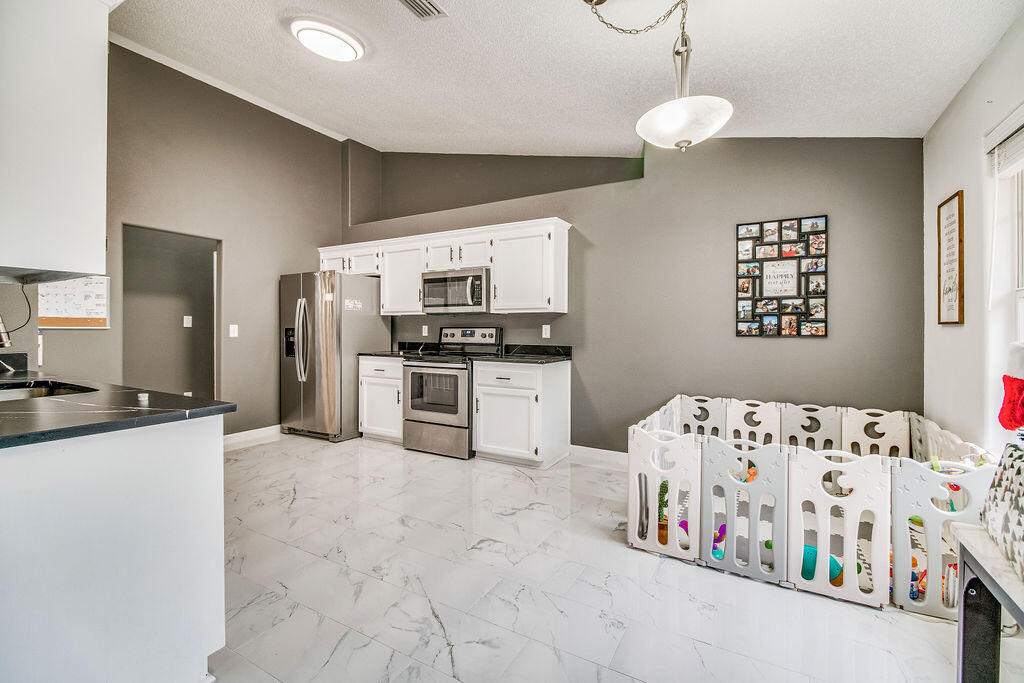 2442 Raider Lane Navarre, FL 32566 - Photo 10 of 46 a kitchen with stainless steel appliances kitchen island granite countertop a sink and cabinets