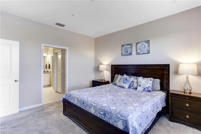 a bedroom with a bed and a lamp on dresser