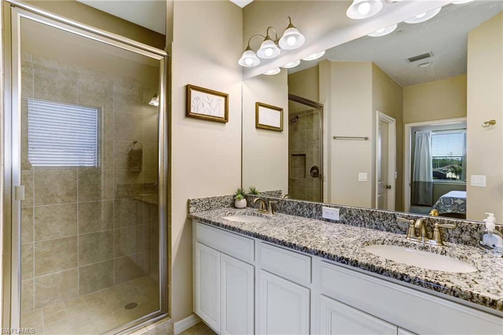 9433 Benvenuto Court, Unit 201 Naples, FL 34119 - Photo 15 of 32 a bathroom with a granite countertop sink mirror and shower